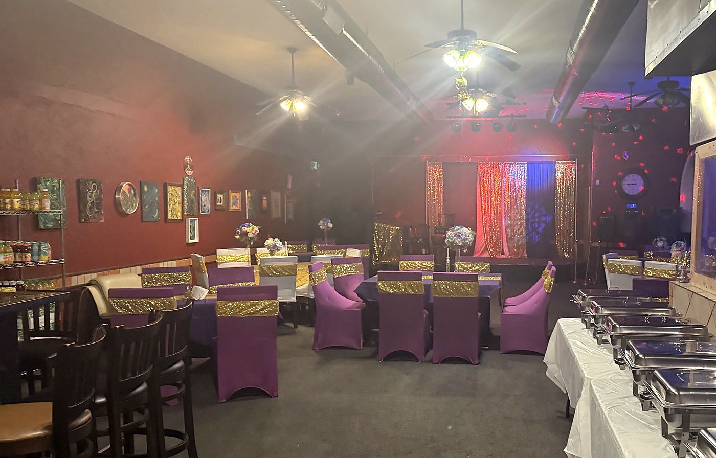 The full room at Ritho Caribbean Spot with tables, stage, and a buffet line